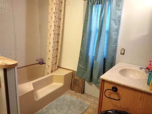 a bathroom with a tub a sink and a large window