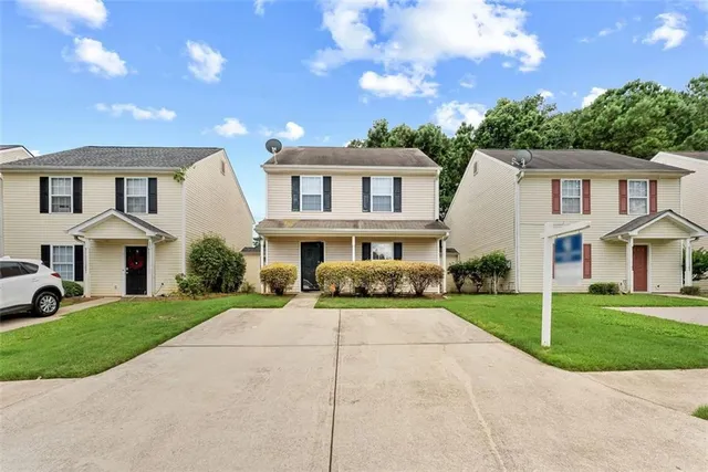 a front view of a house with a garden and trees