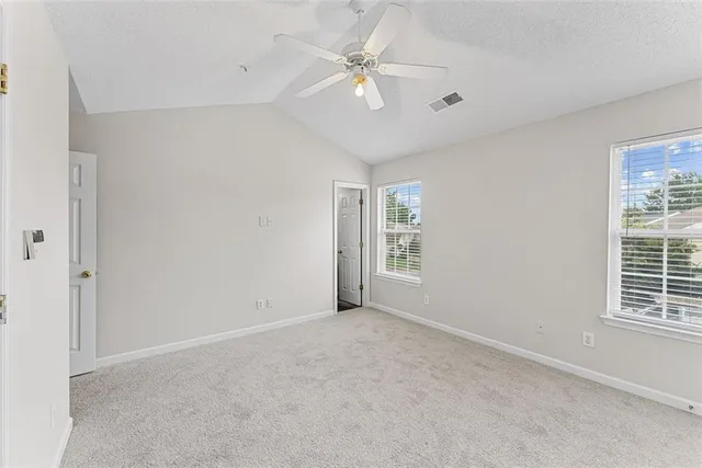 an empty room with windows and fan