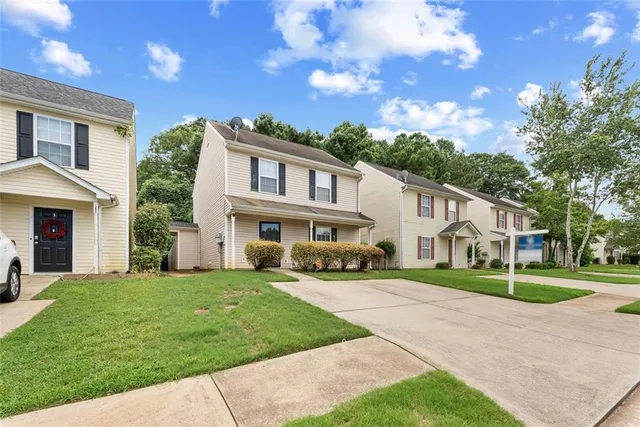 a view of a white house with a big yard and large trees