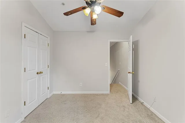 an empty room with chandelier fan and windows