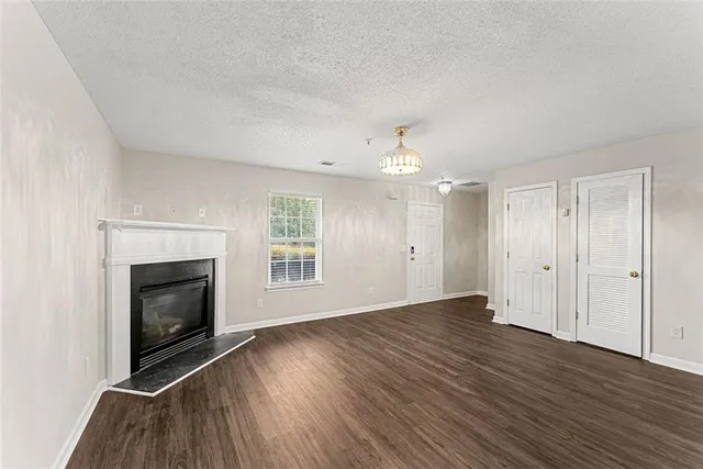 an empty room with wooden floor fireplace and windows