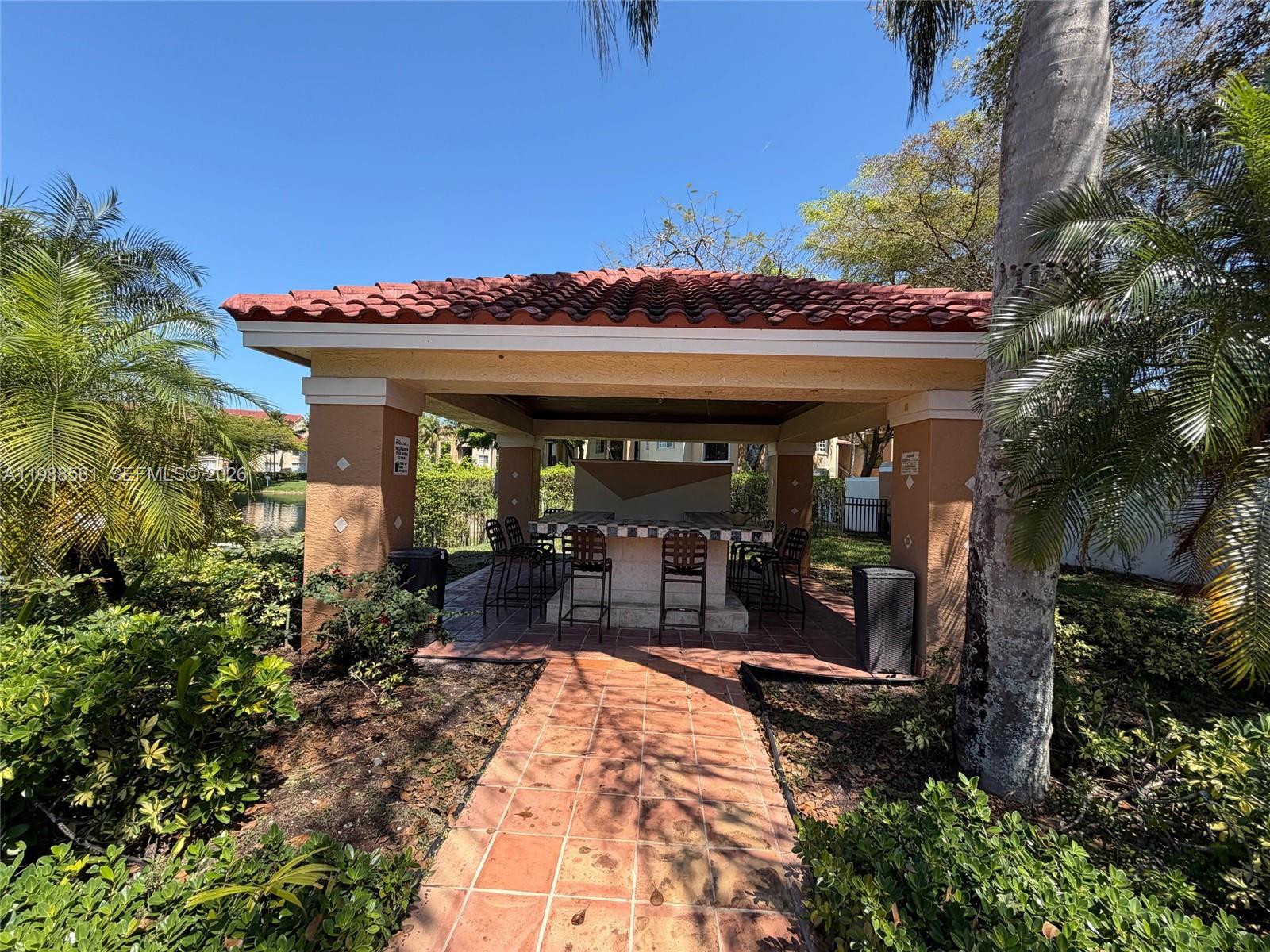2173 Renaissance Boulevard, Unit 101 Miramar, FL 33025 - Photo 24 of 27 a view of a patio with table and chairs potted plants and floor to ceiling window