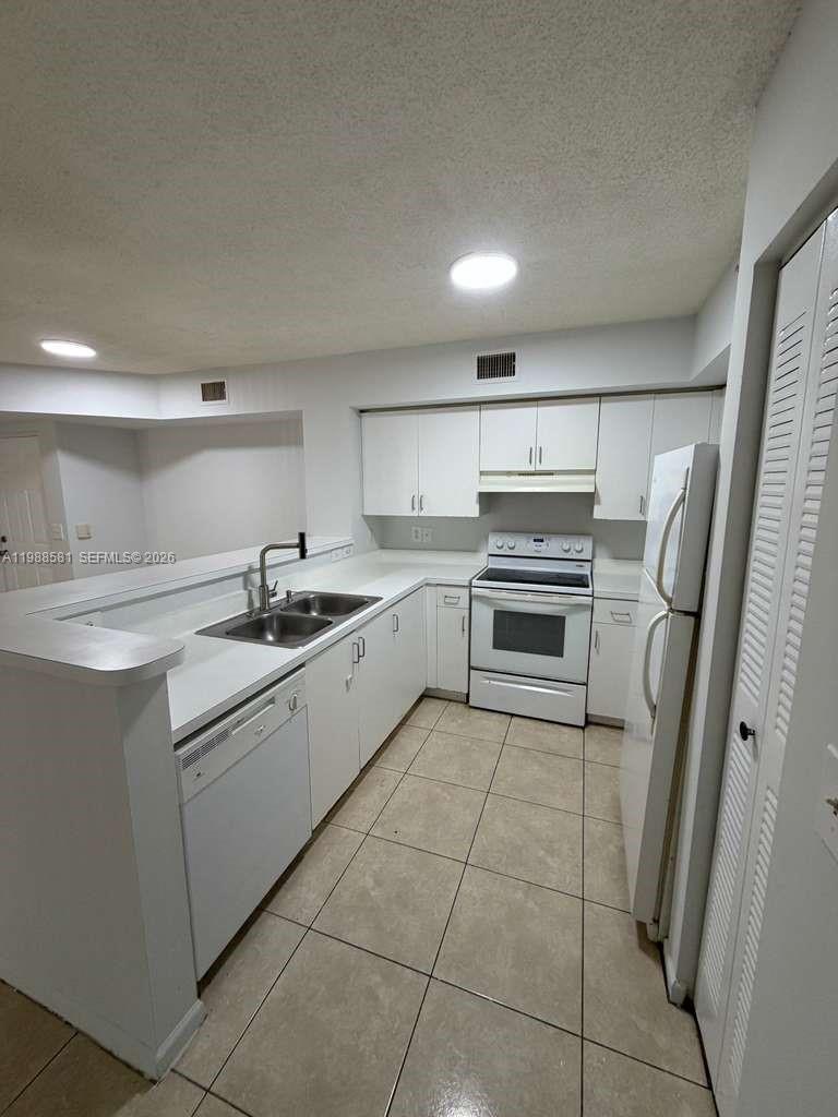 2173 Renaissance Boulevard, Unit 101 Miramar, FL 33025 - Photo 9 of 27 a kitchen with a sink a stove top oven and refrigerator