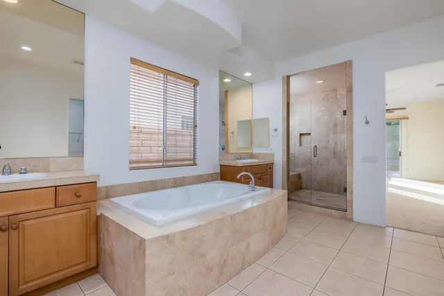 a large spacious bathroom with a granite countertop double vanity sink a mirror and a bathtub