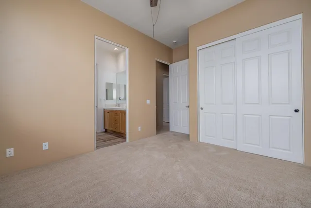 an empty room with chandelier fan and windows