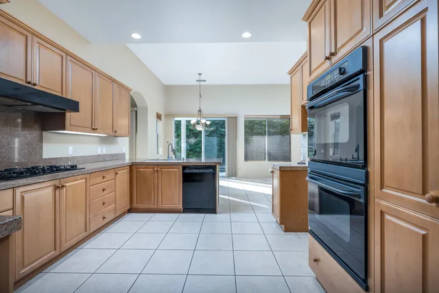 a kitchen with granite countertop a refrigerator and a stove top oven