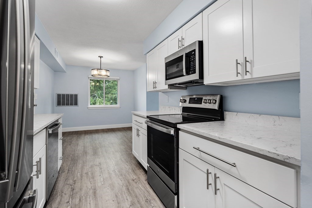 19 Beal's Cove Road, Unit K Hingham, MA 02043 - Photo 2 of 14 a kitchen with stainless steel appliances granite countertop a sink a stove a microwave and wooden cabinets