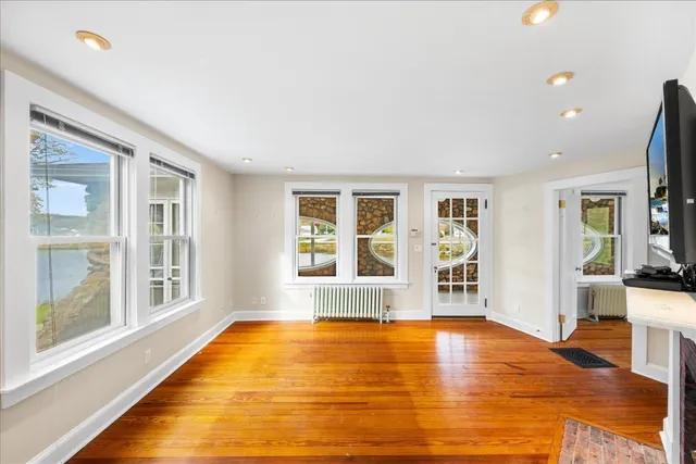 a view of an empty room with wooden floor fireplace and a window