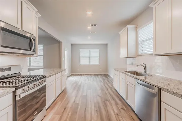 a kitchen with granite countertop wooden cabinets stove top oven and sink