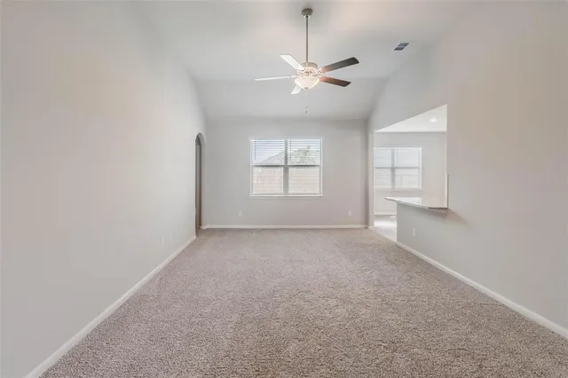 an empty room with windows and chandelier fan