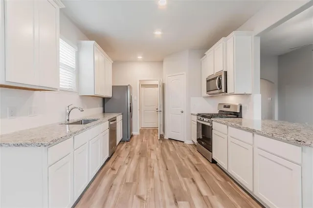 a large kitchen with stainless steel appliances granite countertop a lot of counter space and wooden floors