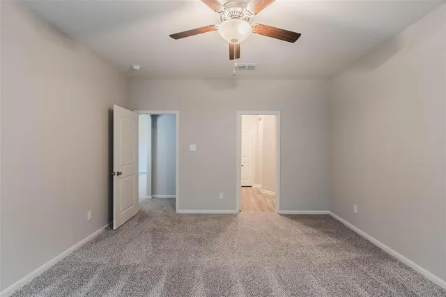 an empty room with chandelier fan and windows