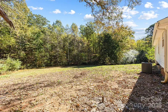 a view of a white house with a yard and large tree