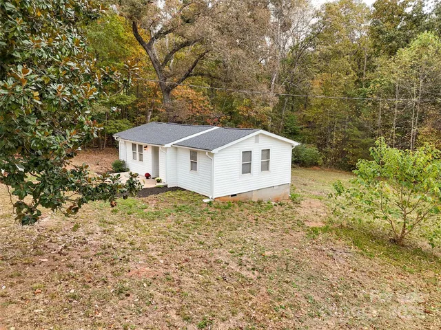 a backyard of a house with large trees and brick wall