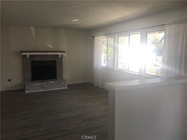 an empty room with wooden floor fireplace and windows
