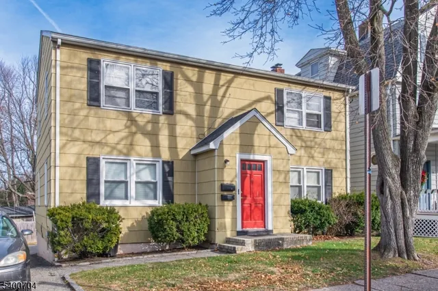 a view of a brick house with plants and large tree