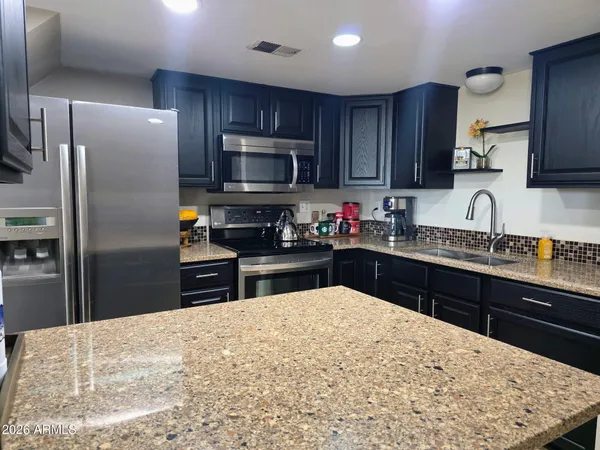 a kitchen with granite countertop wooden cabinets a refrigerator and a sink