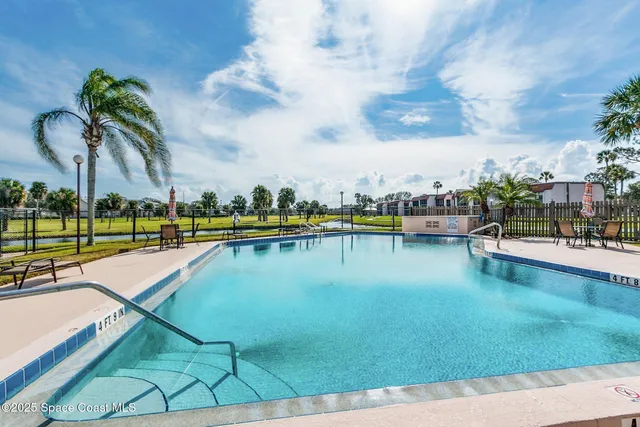a view of a swimming pool with a lawn chairs and plants
