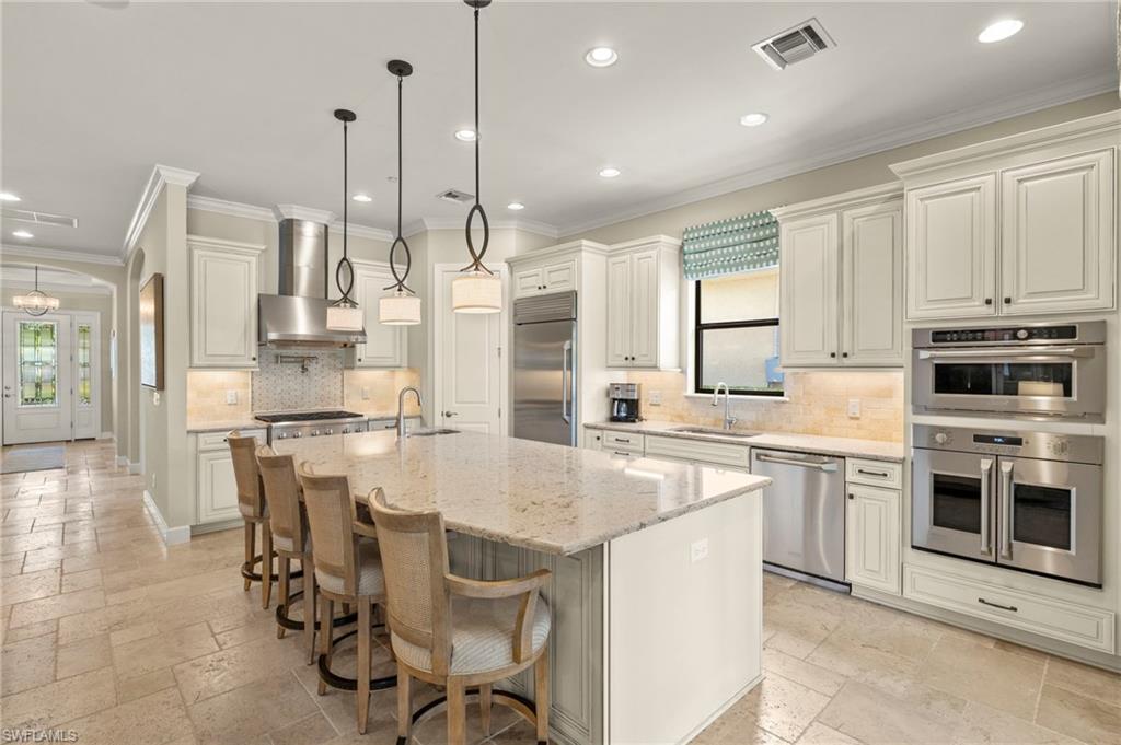 10234 Coconut Road Estero, FL 34135 - Photo 6 of 36 a kitchen with kitchen island a large counter top space appliances and cabinets