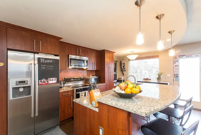 a kitchen with stainless steel appliances granite countertop a refrigerator a stove and a sink