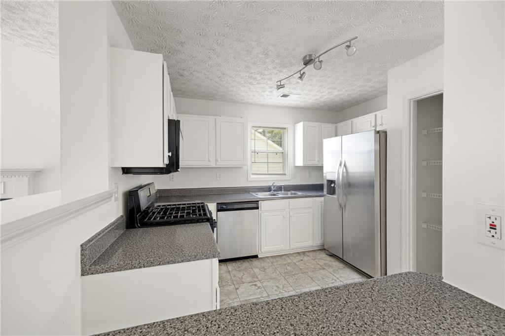 1093 Athena Court Acworth, GA 30101 - Photo 9 of 27 a kitchen with granite countertop a refrigerator a sink and white cabinets