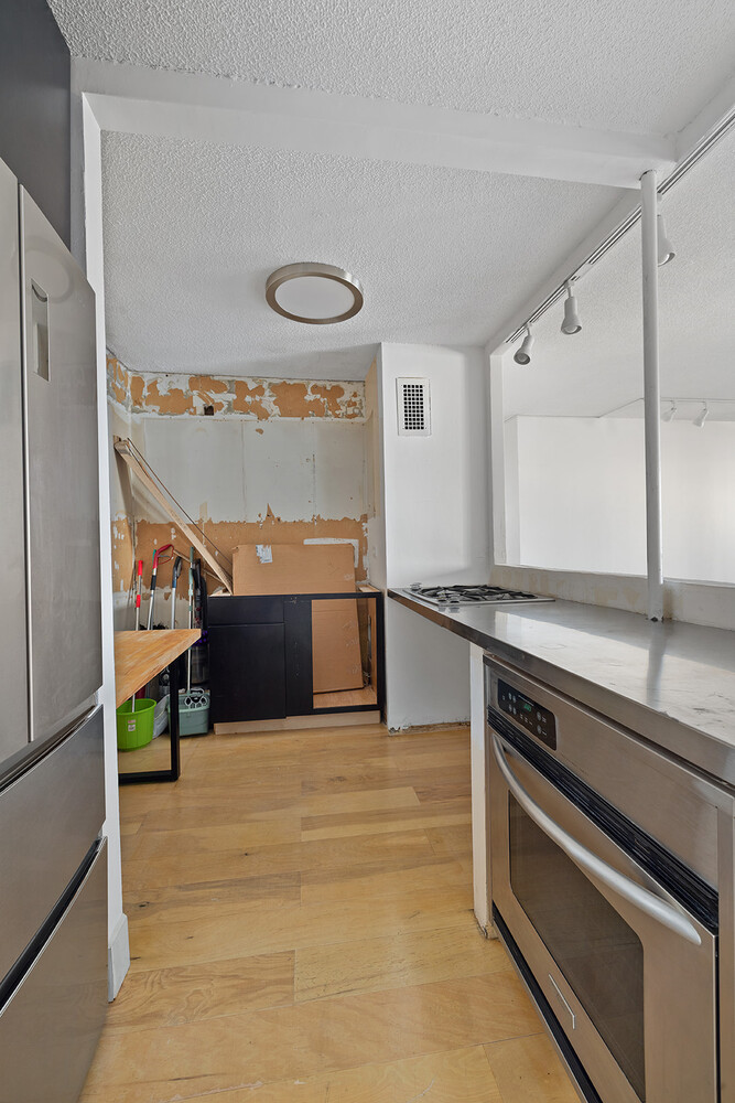 90 Gold Street, Unit 13L Manhattan, NY 10038 - Photo 6 of 10 a view of kitchen with stainless steel appliances wooden floor and a counter top space