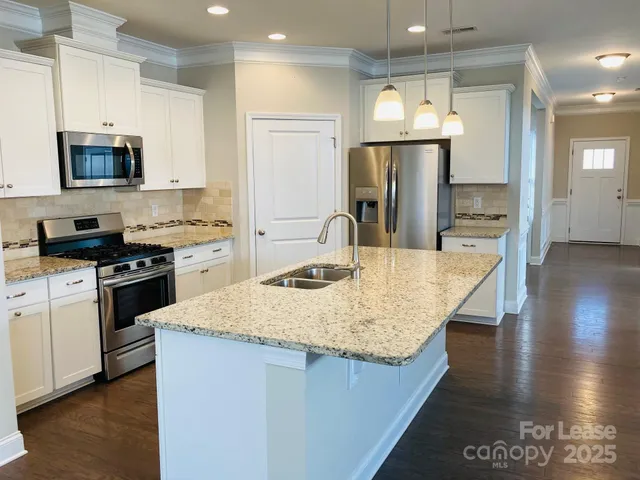 a kitchen with stainless steel appliances granite countertop a sink stove and refrigerator