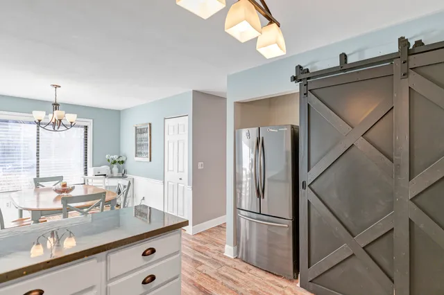 a kitchen with stainless steel appliances kitchen island granite countertop a stove a refrigerator a sink a dining table and chairs with wooden floor