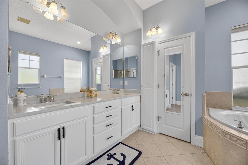 5720 Tortoise Place Apollo Beach, FL 33572 - Photo 33 of 83 a spacious bathroom with a granite countertop sink a mirror a bathtub and shower