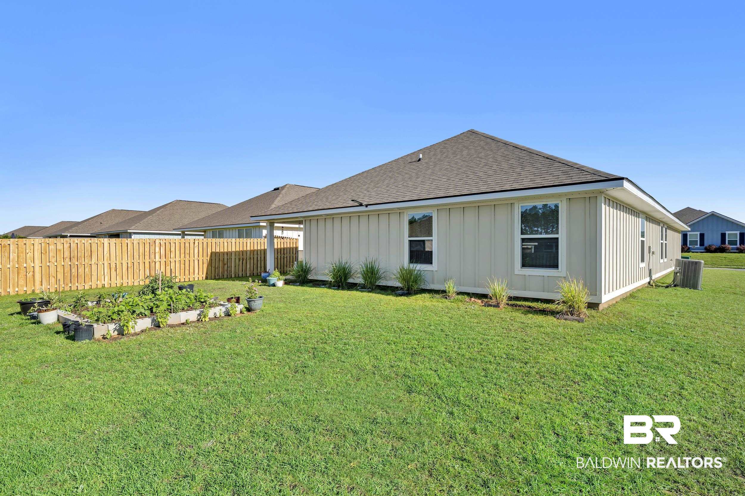 1228 Caper Avenue Foley, AL 36535 - Photo 33 of 54 Expansive green lawn with a raised garden bed and mature shrubbery