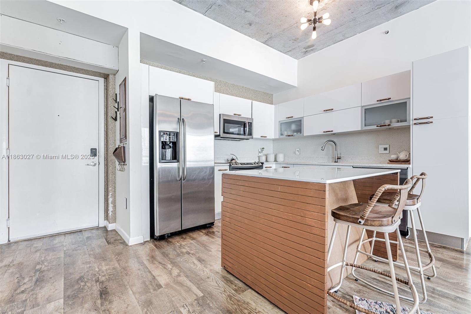 133 Northeast 2nd Avenue, Unit 1208 Miami, FL 33132 - Photo 9 of 33 a kitchen with stainless steel appliances granite countertop a stove top oven a refrigerator a sink dishwasher with a dining table and chairs