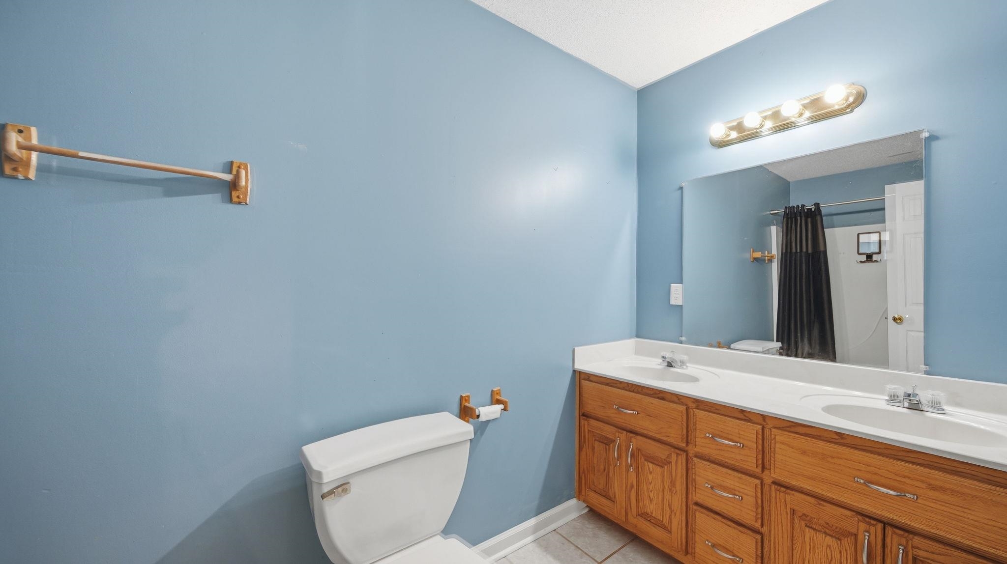 217 Rae Drive Munford, TN 38058 - Photo 30 of 40 Bathroom featuring a dual vanity with wood-finish cabinetry, a large mirror, and a four-light fixture. Full bath upstairs.