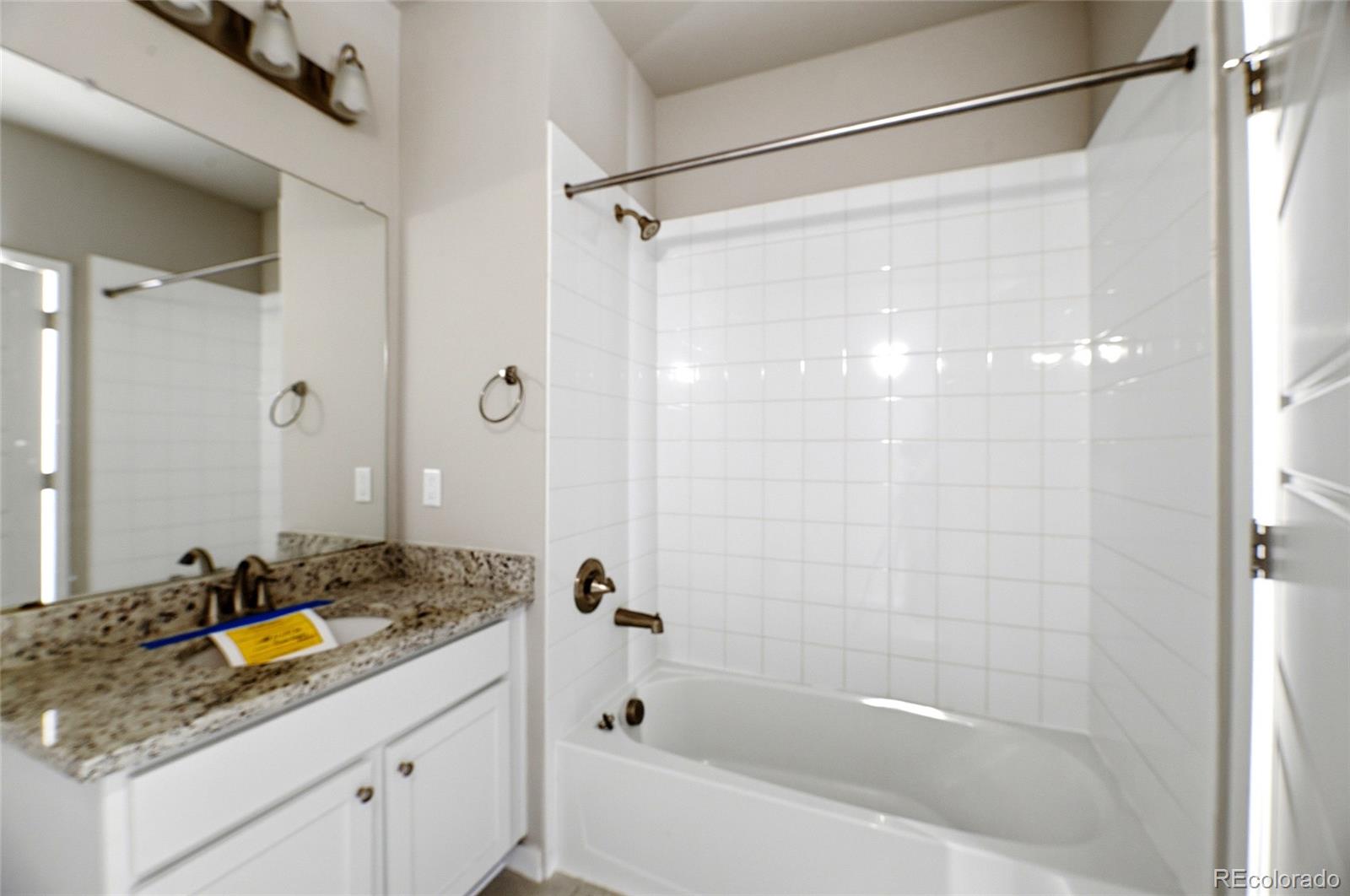 9291 Twenty Mile Road, Unit 207 Parker, CO 80134 - Photo 13 of 25 a bathroom with a granite countertop sink a mirror a bathtub and shower