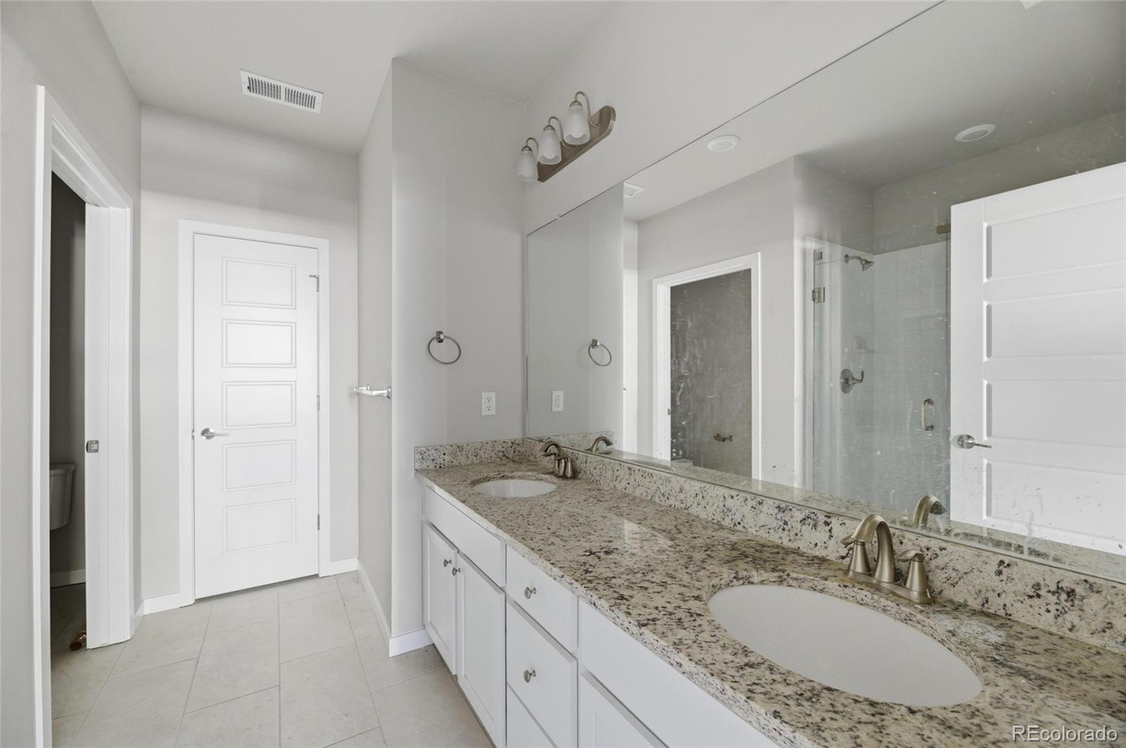 9291 Twenty Mile Road, Unit 207 Parker, CO 80134 - Photo 18 of 25 a bathroom with a granite countertop double vanity sink and a mirror