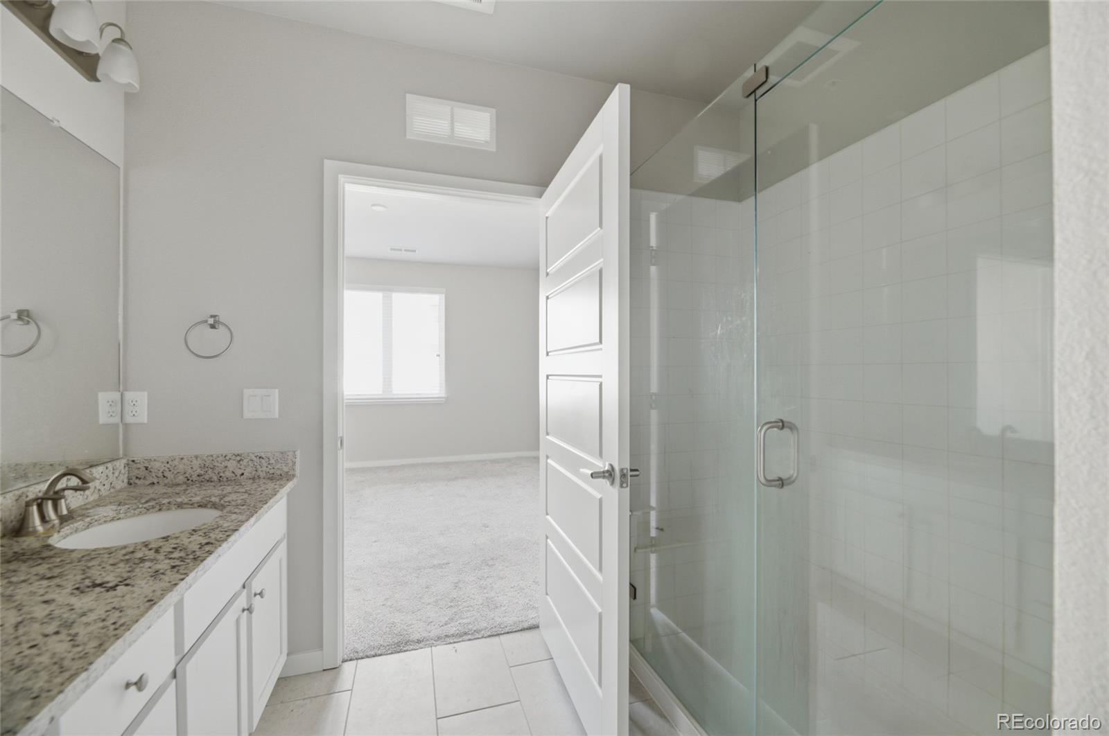 9291 Twenty Mile Road, Unit 207 Parker, CO 80134 - Photo 19 of 25 a bathroom with a granite countertop sink shower and a mirror