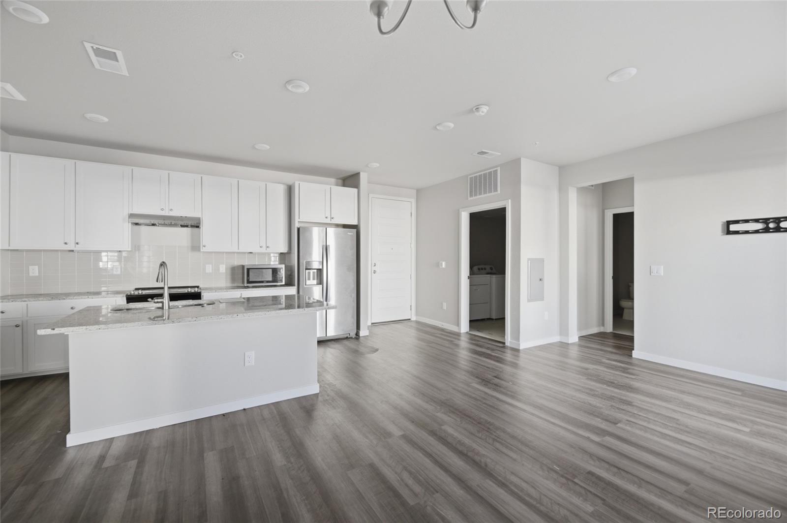 9291 Twenty Mile Road, Unit 207 Parker, CO 80134 - Photo 4 of 25 a kitchen with stainless steel appliances granite countertop a refrigerator a stove and white cabinets with wooden floor
