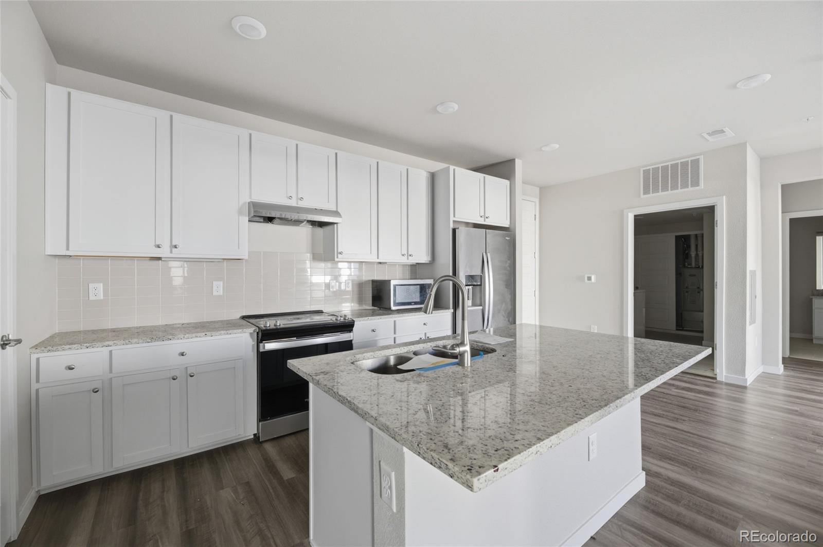 9291 Twenty Mile Road, Unit 207 Parker, CO 80134 - Photo 5 of 25 a kitchen with stainless steel appliances granite countertop a sink dishwasher and stove with wooden floor