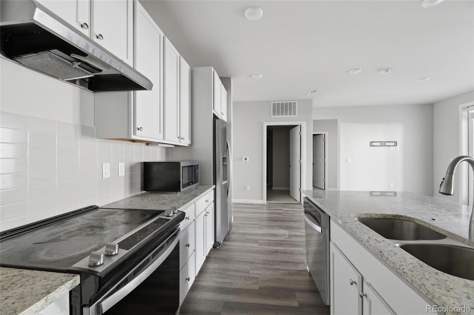 9291 Twenty Mile Road, Unit 207 Parker, CO 80134 - Photo 6 of 25 a kitchen with stainless steel appliances a stove a sink and a refrigerator