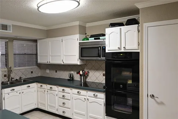 a kitchen with granite countertop white cabinets and black appliances