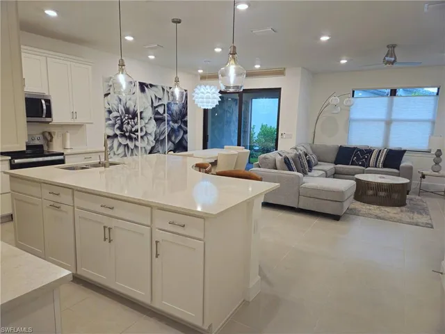 a kitchen with kitchen island granite countertop a sink and white cabinets