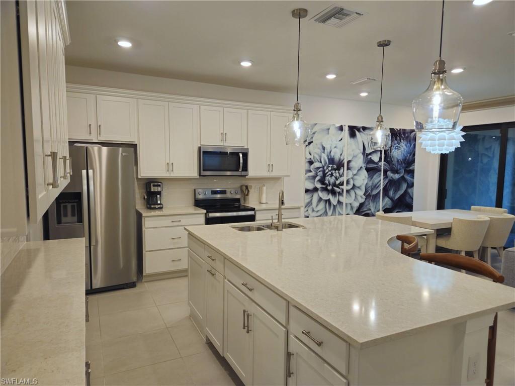 Undisclosed Address Naples, FL 34119 - Photo 3 of 50 a view of a kitchen with kitchen island a sink stainless steel appliances and cabinets