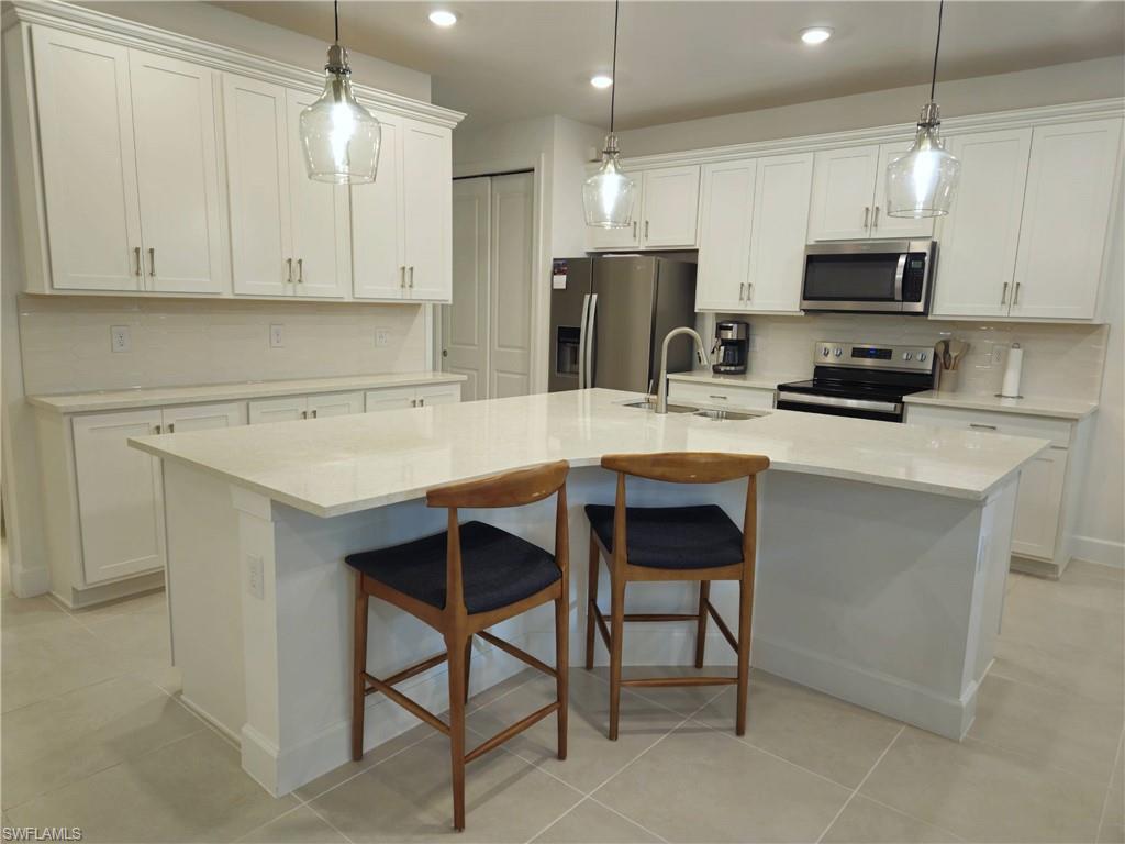 Undisclosed Address Naples, FL 34119 - Photo 10 of 50 a kitchen with stainless steel appliances a stove a sink refrigerator and a white cabinets with wooden floor