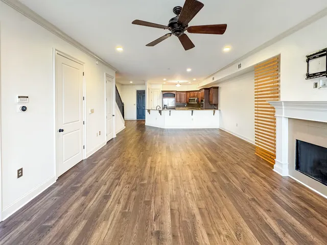a view of a kitchen with wooden floor a ceiling fan and windows