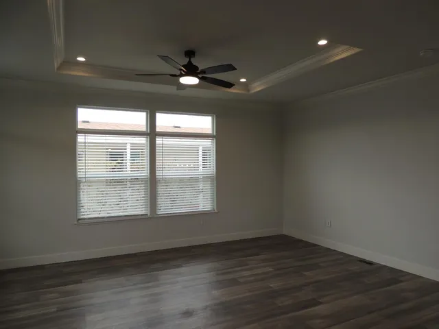 an empty room with wooden floor fan and windows