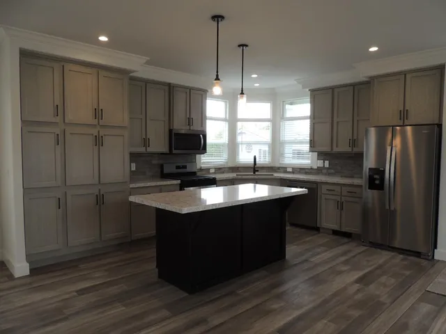 a kitchen with kitchen island granite countertop a sink cabinets and stainless steel appliances