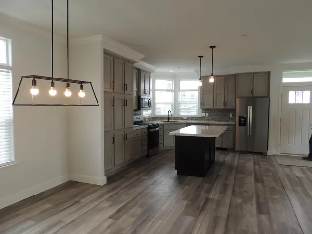 a kitchen with a refrigerator a sink dishwasher and a stove with wooden floor