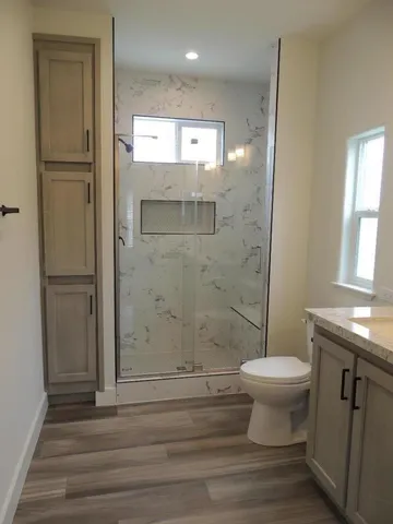 a bathroom with a shower a toilet a sink and a window