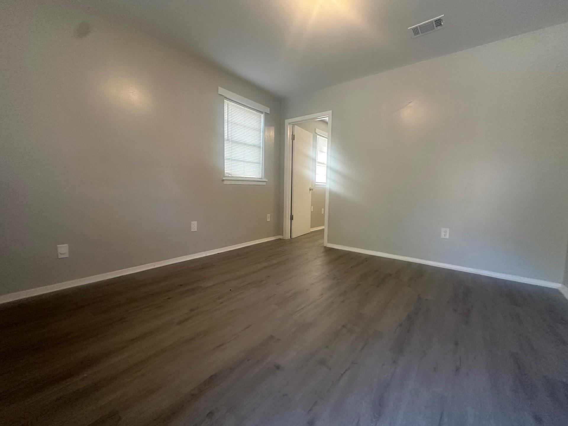 499 Baltimore Street Memphis, TN 38111 - Photo 4 of 9 an empty room with wooden floor and windows