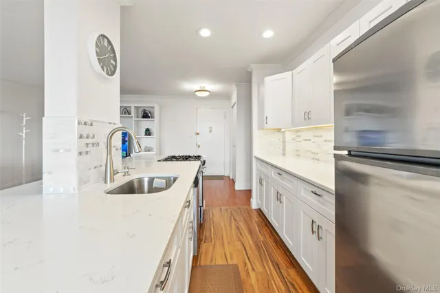 a large white kitchen with a large window a sink and stainless steel appliances